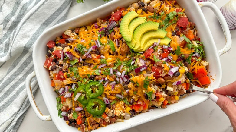 Mexican cauliflower rice casserole with cheese, tomatoes, jalapenos, and avocado