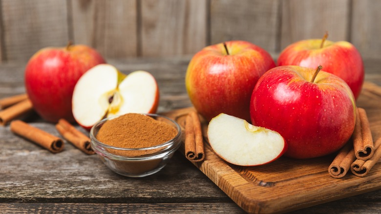 Fresh apples and cinnamon on wooden table