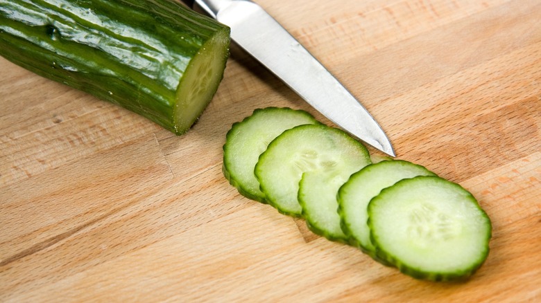 Thinly sliced cucumbers on a cutting board