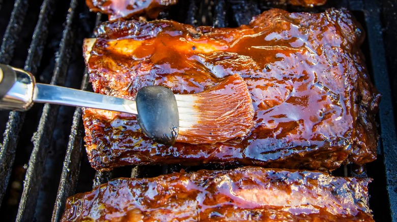Basting barbecue sauce on ribs