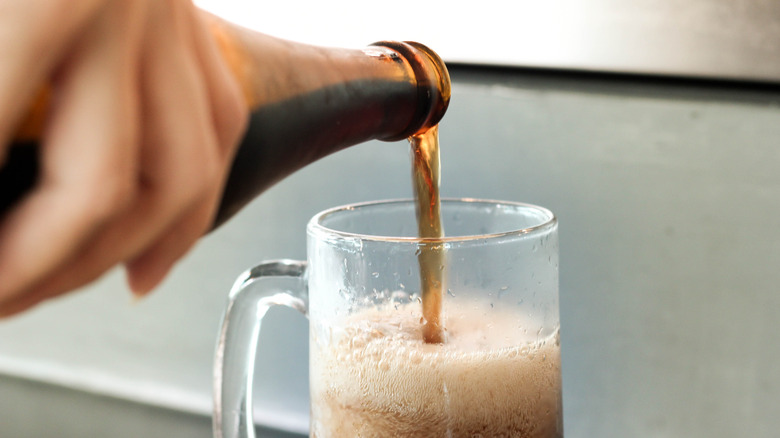 pouring bottle root beer in mug
