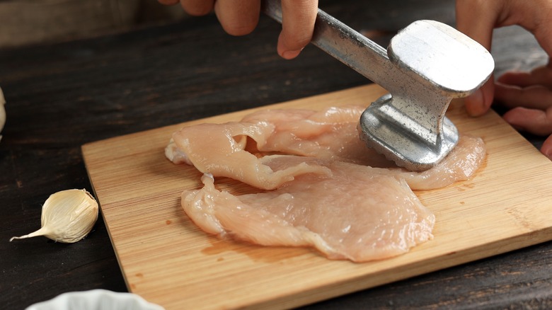 Meat mallet pounding raw chicken