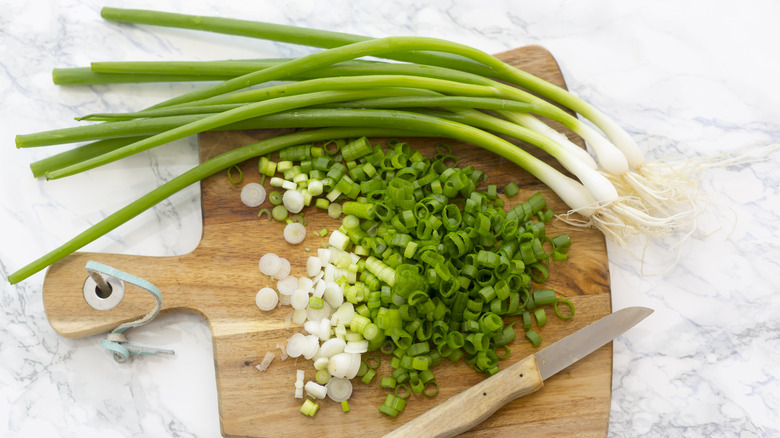 cut and whole green onion on cutting board