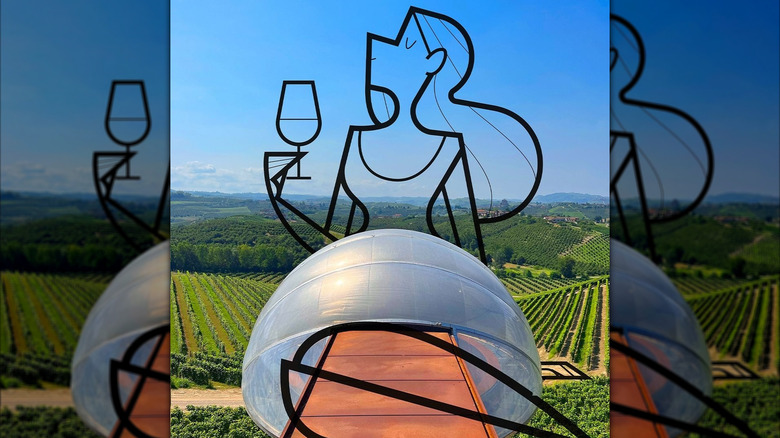 iron sculpture of woman drinking wine with a lush vineyard