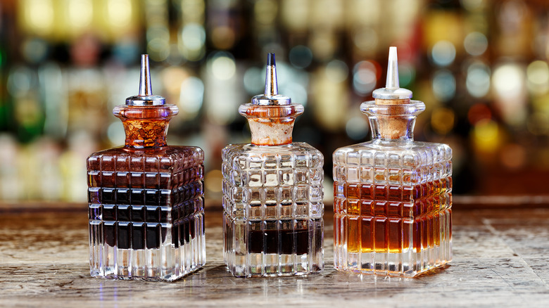 Three glass decanters of cocktail bitters