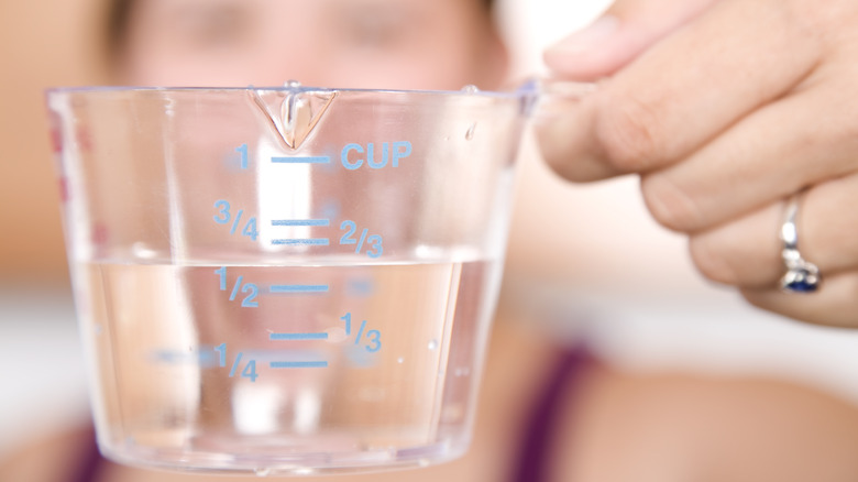 Person measuring water in cup