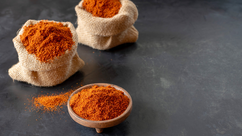 Burlap bags of berbere spice mix next to a small wooden bowl full