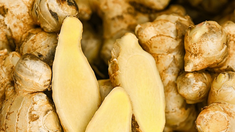 Ginger root sliced open among whole ginger