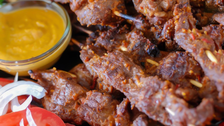 skewered meat on plate with yellow dip