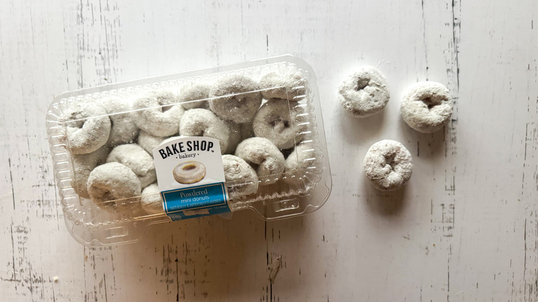 Powdered mini donuts and container on a white board