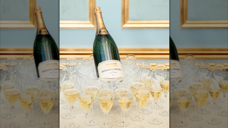 bottle of sparkling wine in ice bucket with many glasses