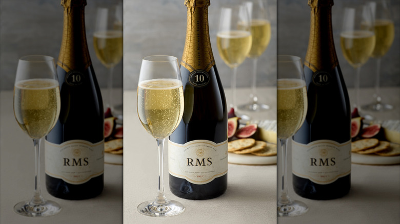 bottle of sparkling wine with glass and crackers