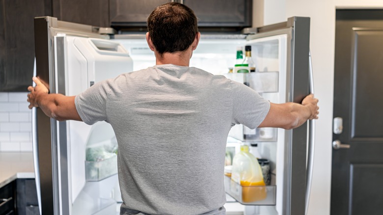 man looking inside fridge
