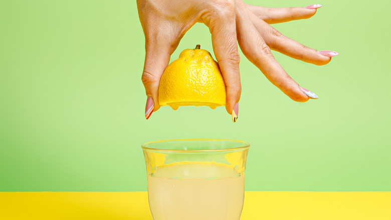 hand squeezing lemon into glass