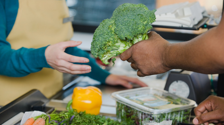 Customer handing cashier broccoli