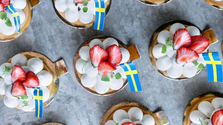 strawberry tartlets with Swedish flags on gray surface