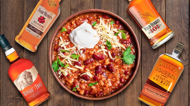 Four bourbon bottles with a bowl of chili