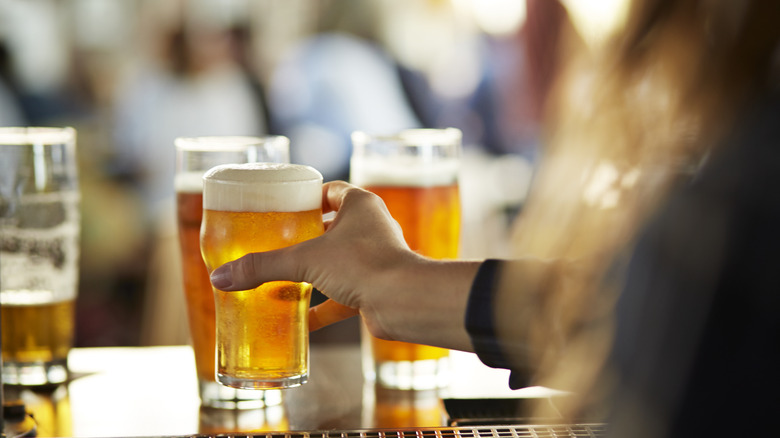 Hand grabbing pint of beer off a bar