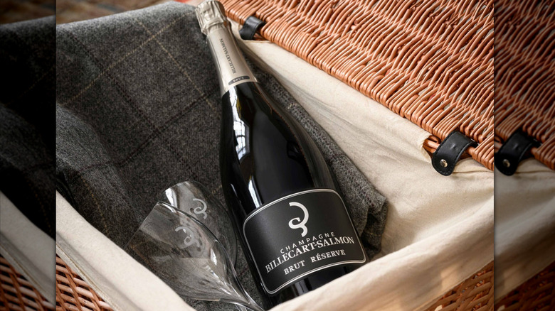 bottle of champagne in picnic basket with two glasses and a blanket