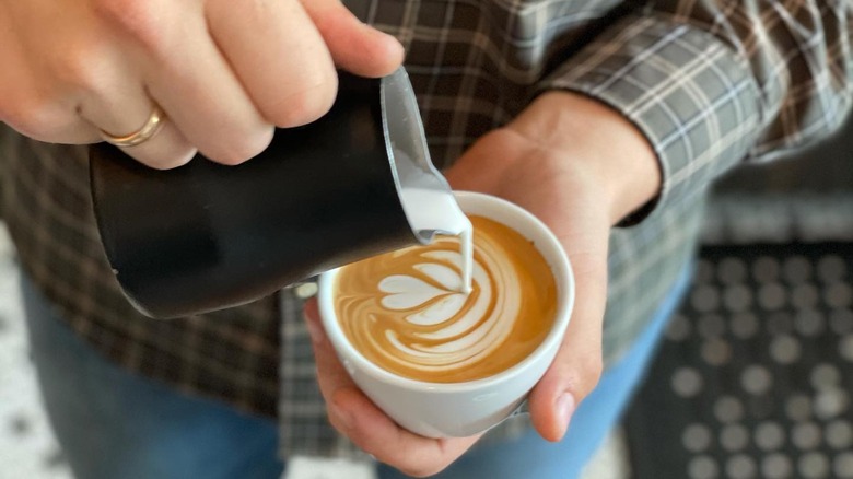 barista pouring latte into mug