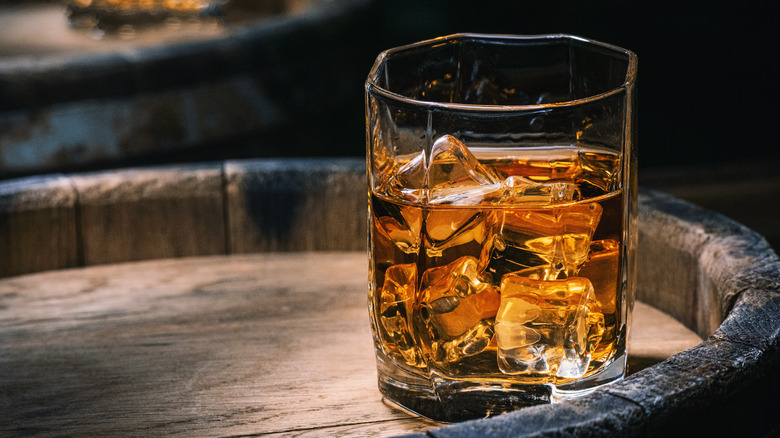 Whiskey glass sitting atop a barrel 