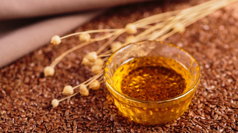 Flaxseed oil in small glass bowl over top of whole flaxseeds