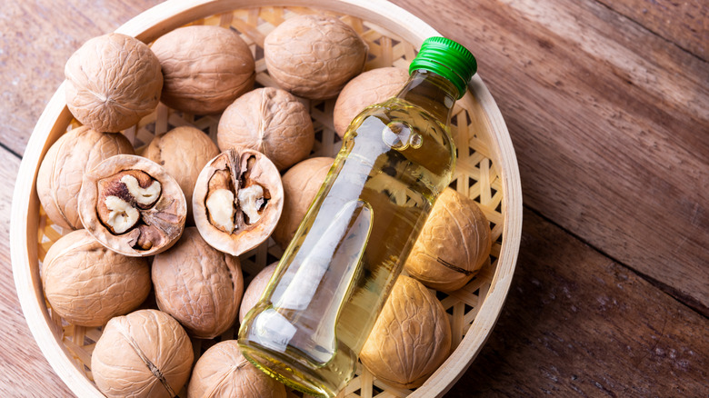 Walnuts in wooden bowl with a bottle of walnut oil