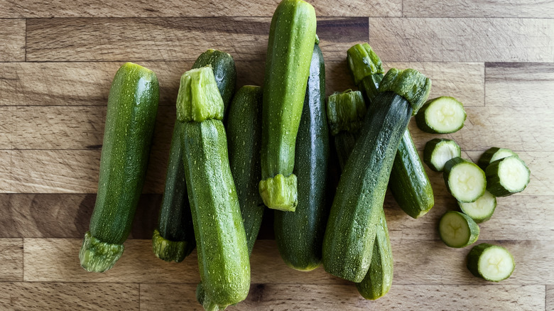 Chopped and whole zucchini on wooden cutting board