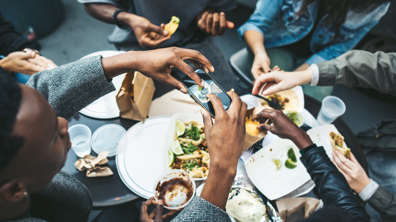 Person with friends photographing food