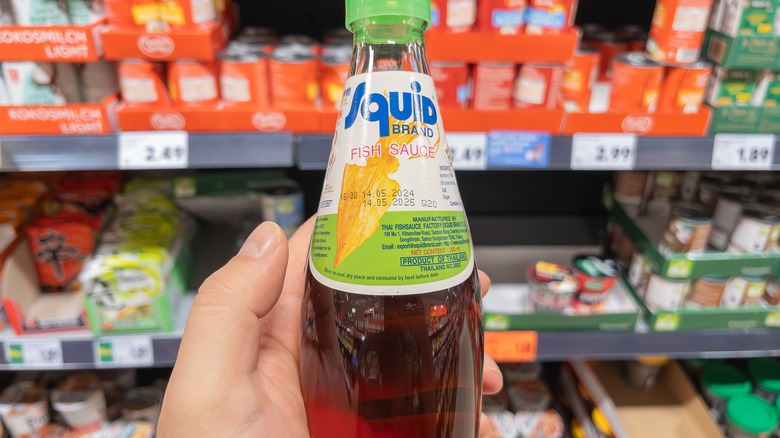 person holding bottle of fish sauce at store