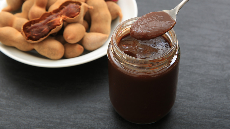 person spooning from jar of tamarind paste