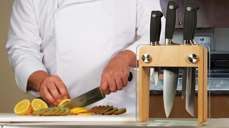 Block of Mercer knives, with a chef using one in the background