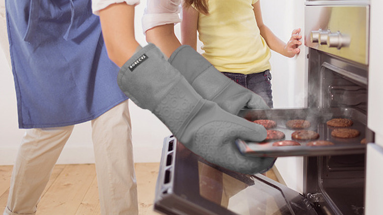 Person wearing Rorecay mitts holding an oven tray of steaming cookies