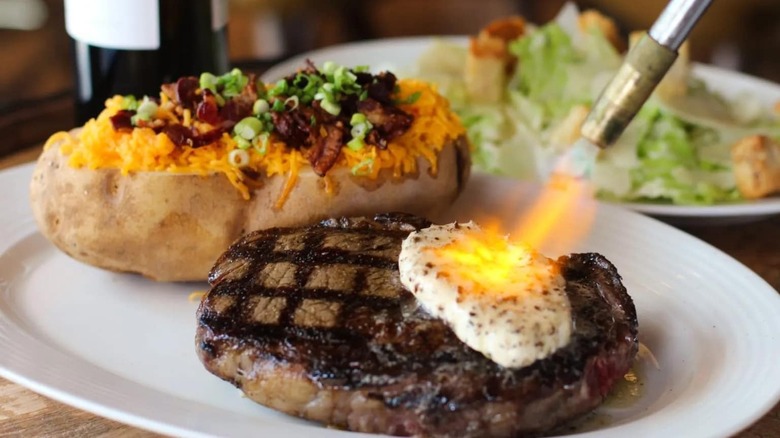 14 oz. Mishima Wagyu strip with a baked potato and a Caesar salad on a plate