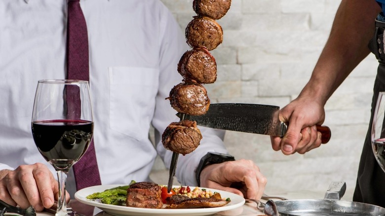 person with knife serving Brazilian churrasco