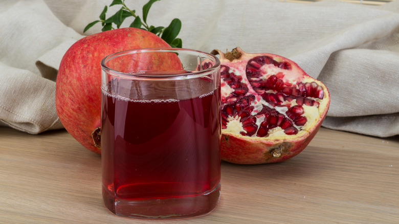 Pomegranate juice in glass, pomegranates