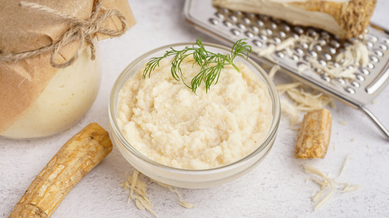 Fresh grated horseradish in bowl topped with fresh dill sprig