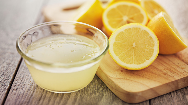 Lemon juice  in small glass bowl with lemons