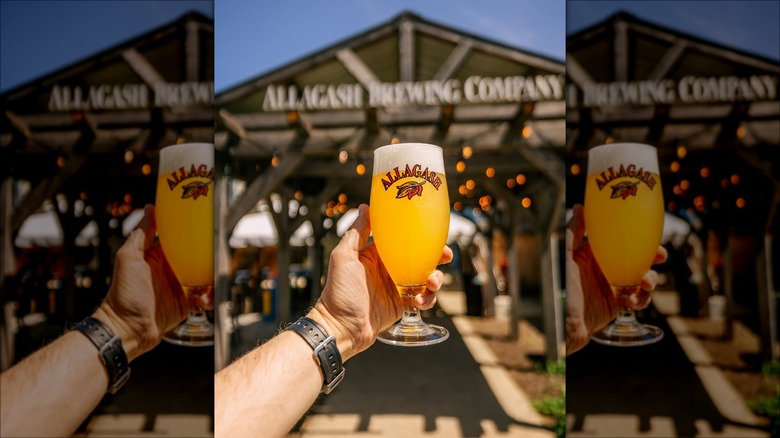 holding beer in front of Portland Allagash Brewery