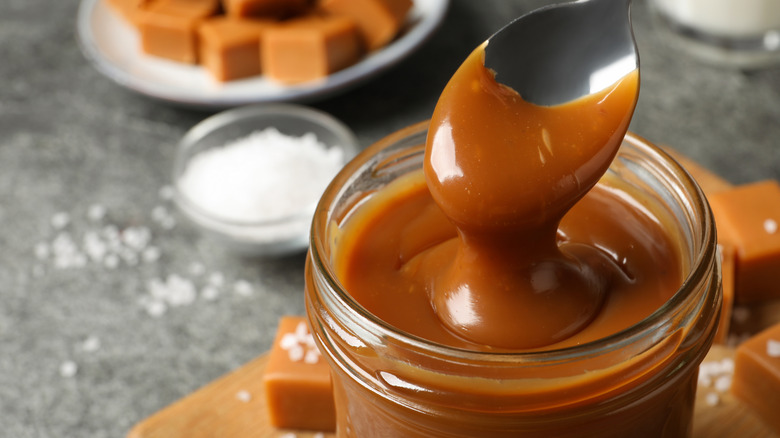 Caramel sauce being spooned out of a jar