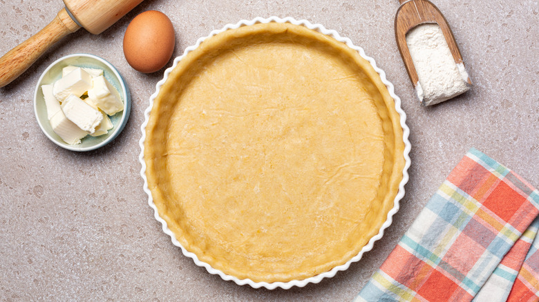 Raw and unbaked pie crust on a table with ingredients