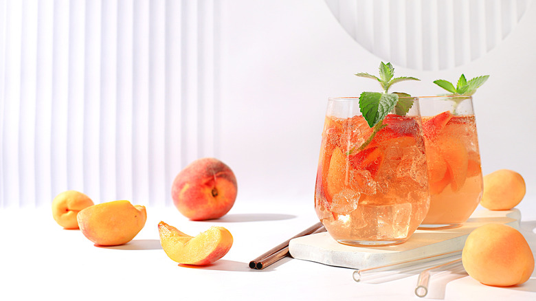 Two glasses of iced tea with straws, peaches, and mint