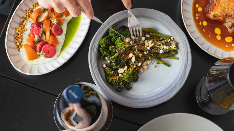 Fork digging into broccolini and colorful veggie plate at Sunday Vinyl