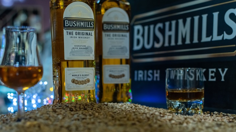 Two bottles of Bushmills with glasses on grains