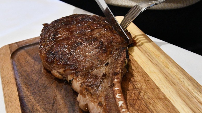 Cutting into steak on cutting board