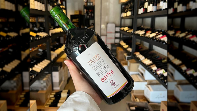 hand holding 1L bottle of red wine