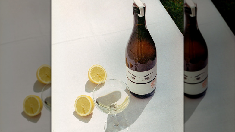 bottle of white wine with coupe glass and lemons