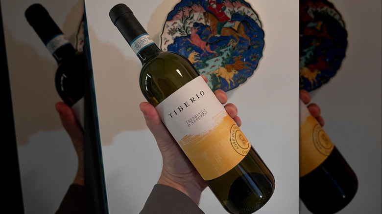 hand holding bottle of white wine
