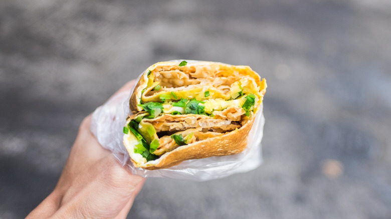 Hand holding a jianbing crepe