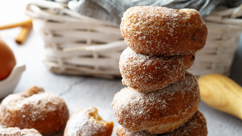 fried donuts stacked on top of one another in front of basket